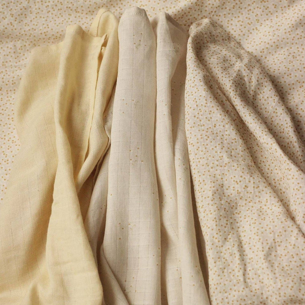 Three different wild camomile muslin squares on a textured beige background
