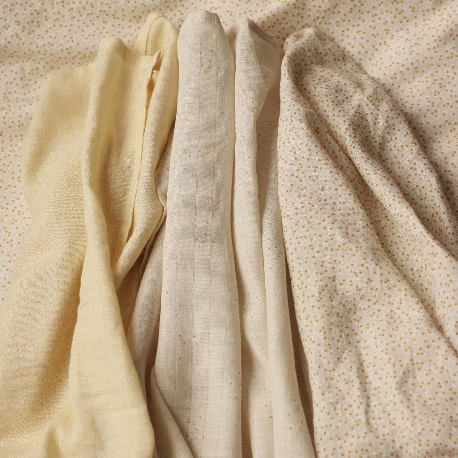 Three different wild camomile muslin squares on a textured beige background