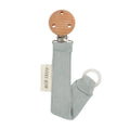 Pacifiier holder with wooden base and ribbed fabric strap on a white background