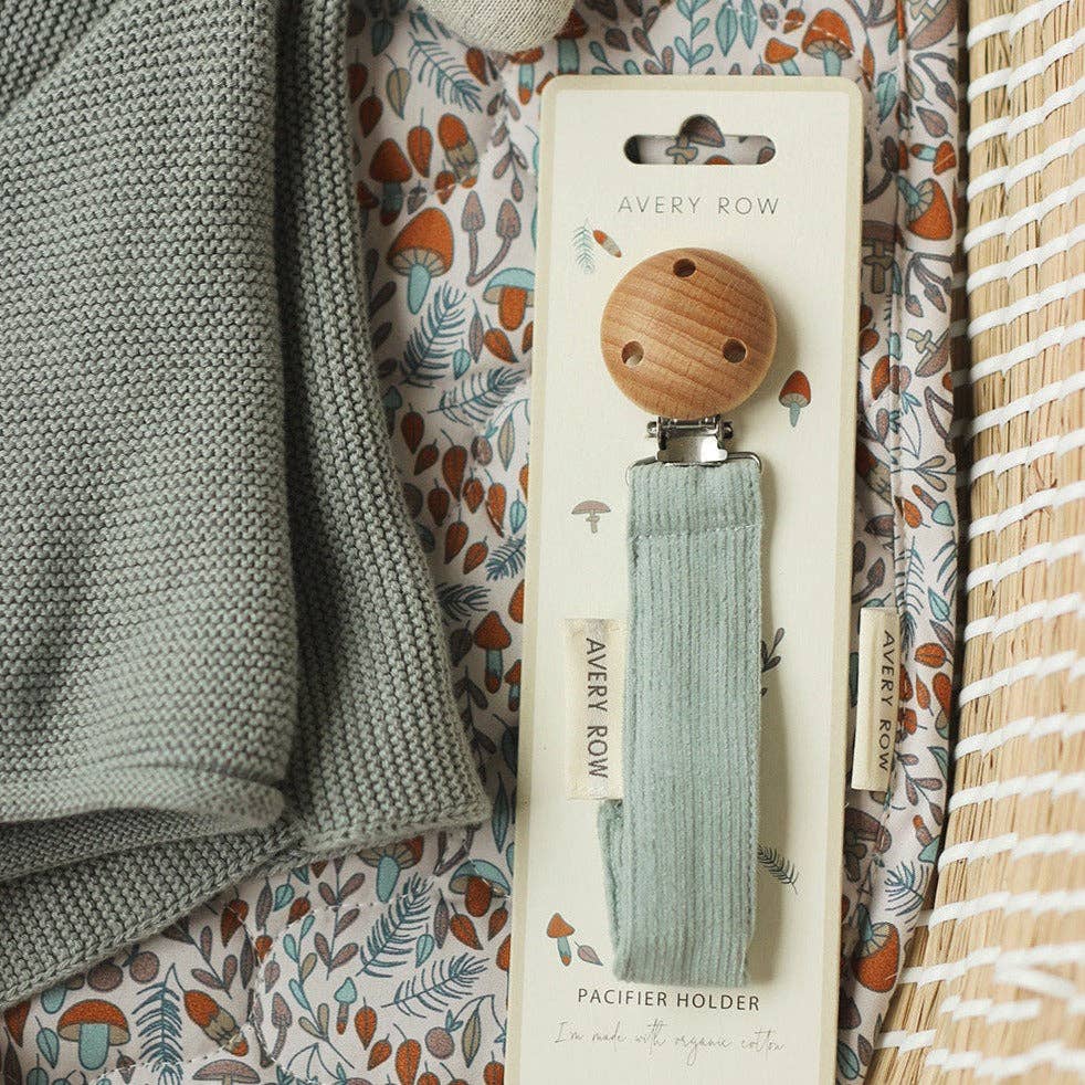 Avery Row pacifier holder on a patterned fabric background