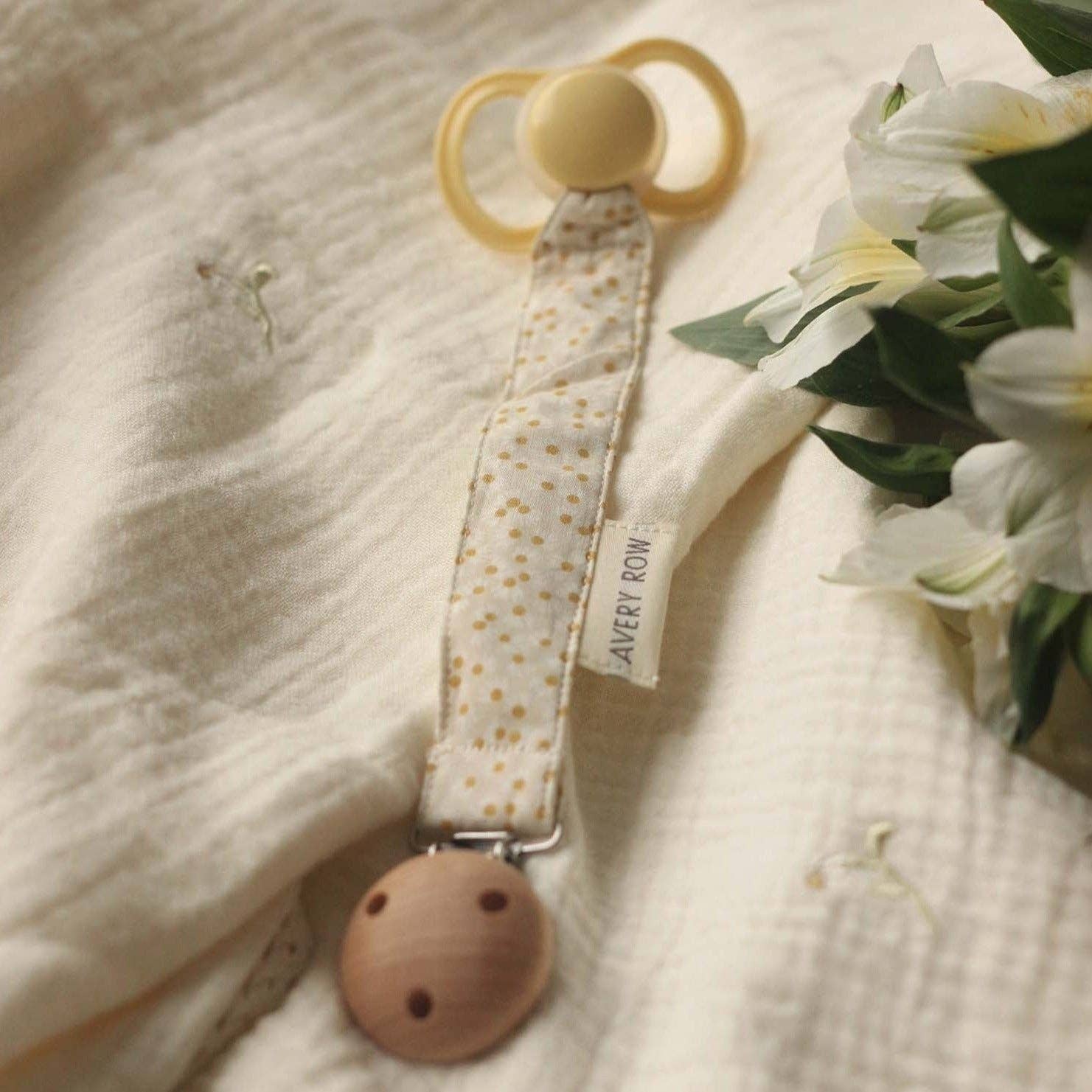 Baby pacifier clip with floral design on a soft fabric background