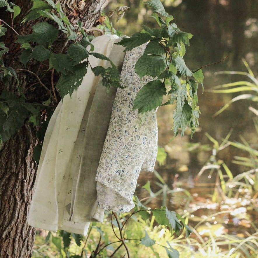 3 patterned muslins hanging from a tree branch in a natural setting.