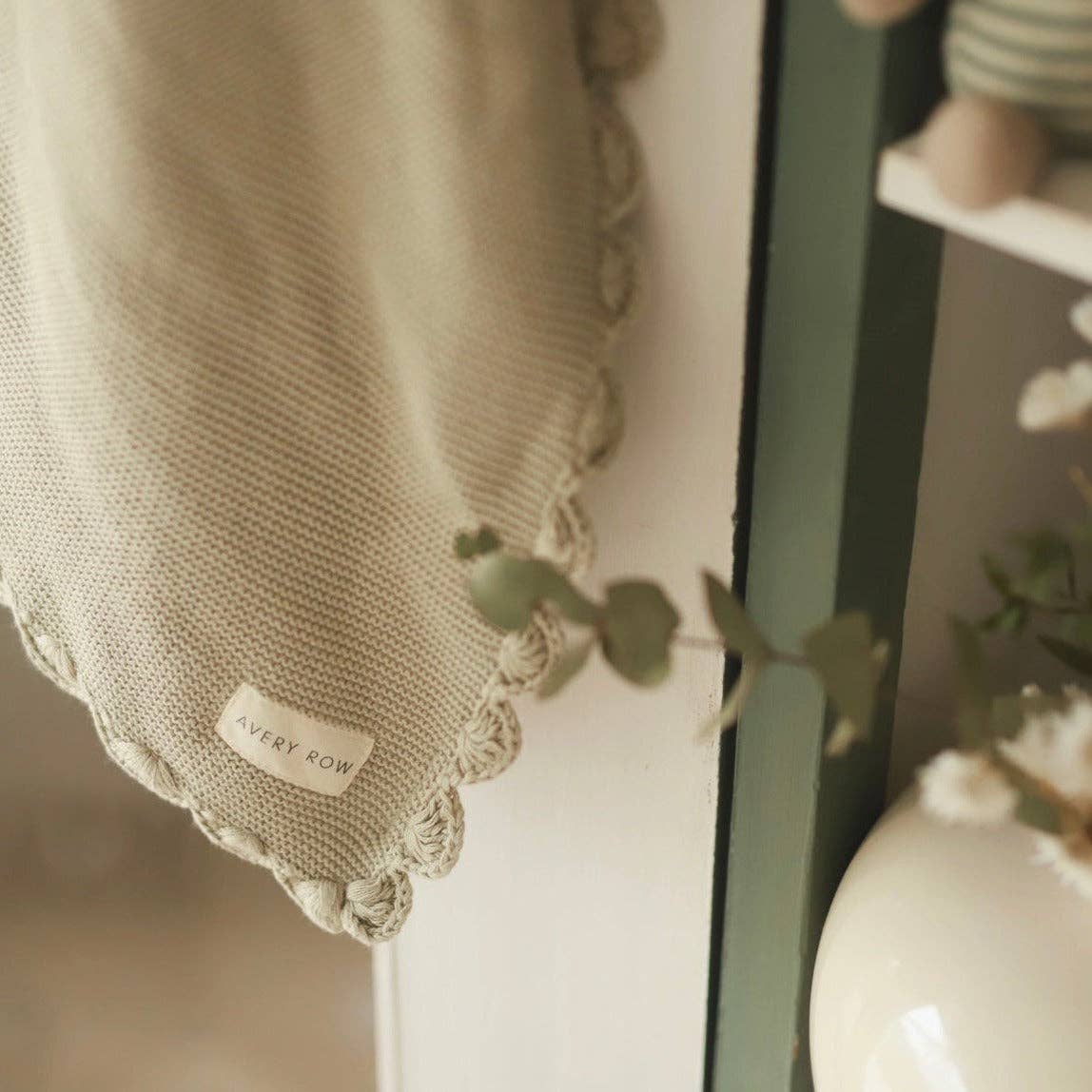 Textured Willow blanket with a brand label next to a vase and plant