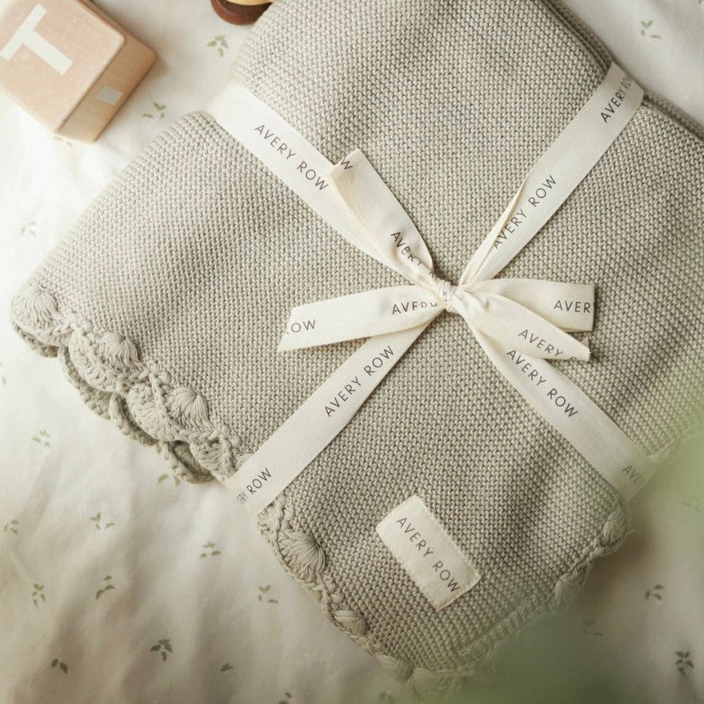 Textured blanket with 'Avery Row' labels tied around it on a light background
