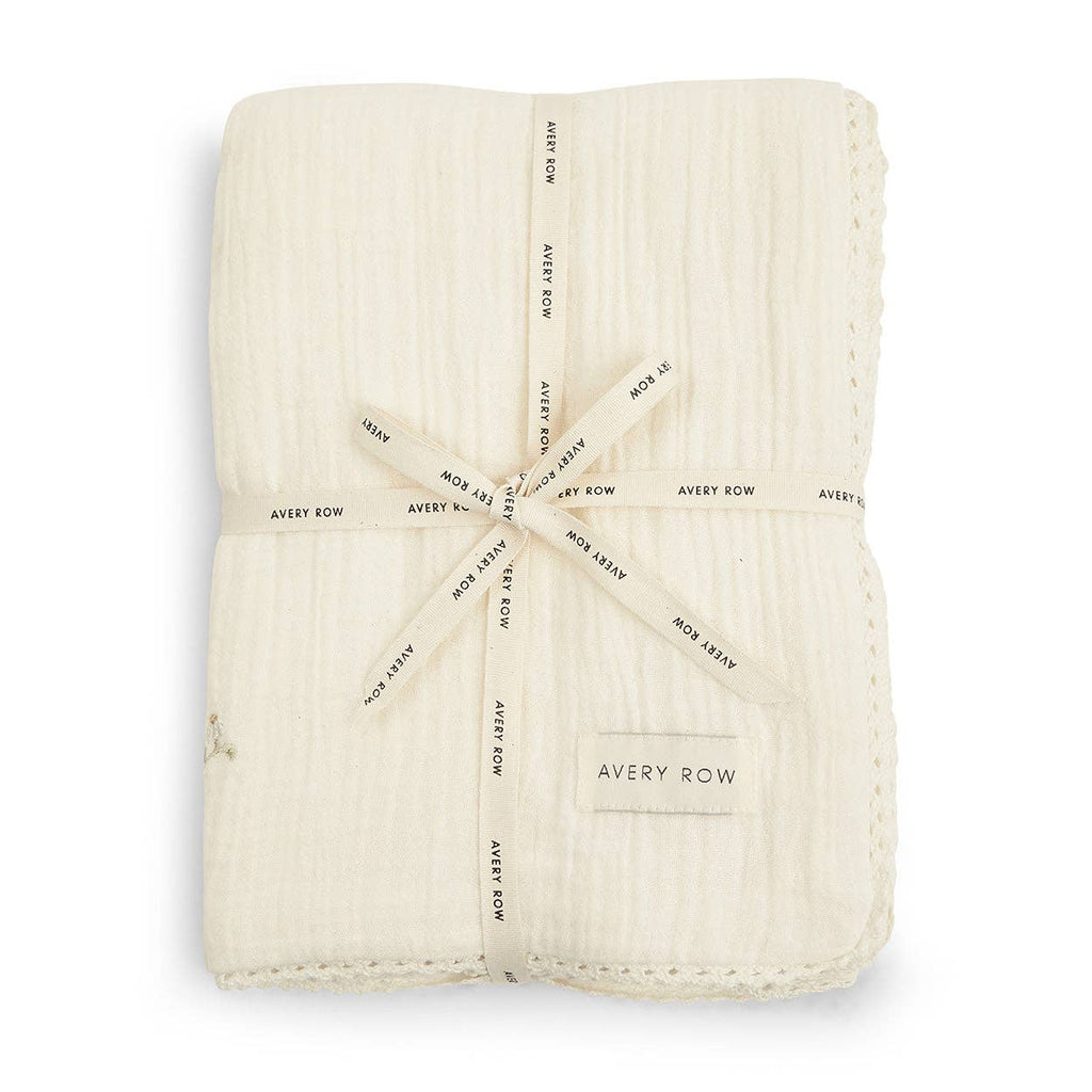 Folded cream-colored baby blanket with 'Avery Row' branding on a white background