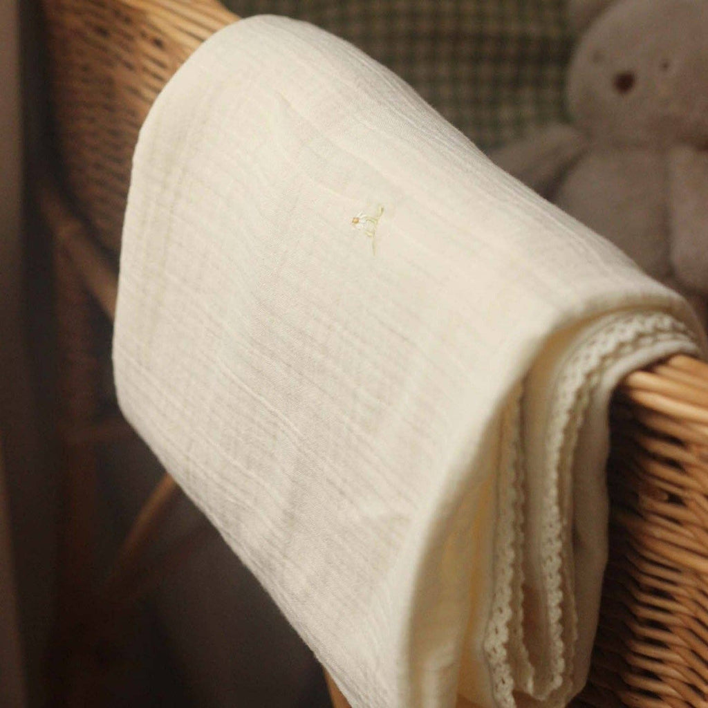 Folded muslin blanket on a wicker basket with a soft focus background