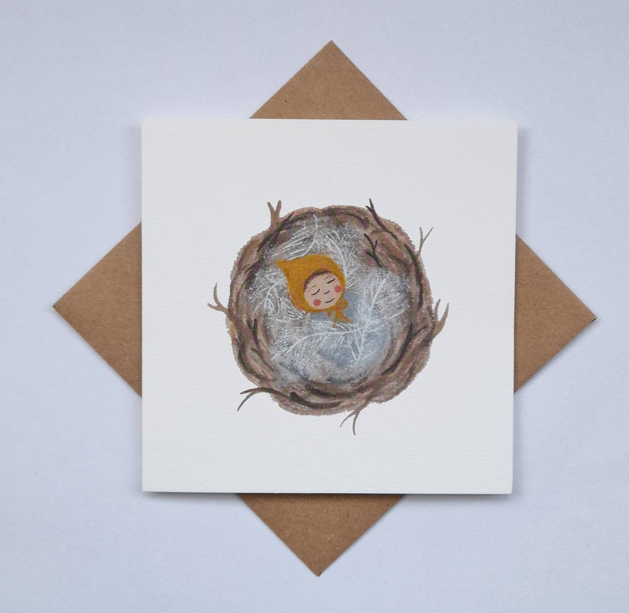 Card with a nest illustration featuring a baby in a yellow outfit, on a white background with a brown envelope.