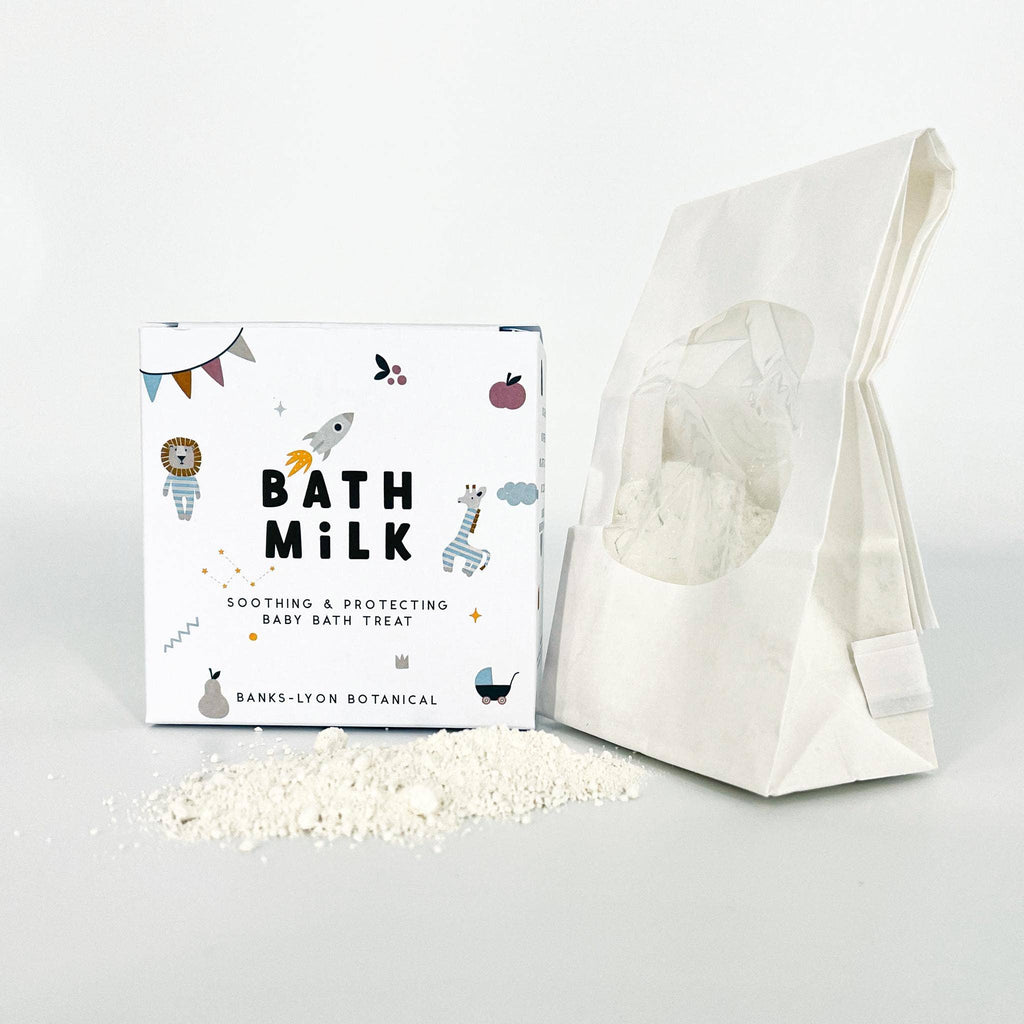 Bath milk packaging with a white bag and visible bath milk crystals on a light gray background