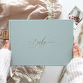 Light blue baby journal held by a person with a blurred background