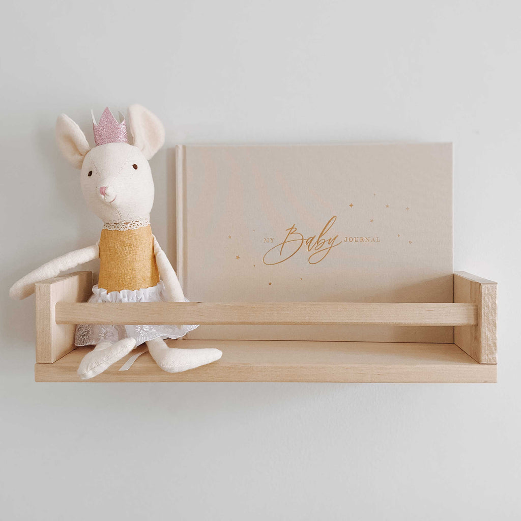 Baby Journal on a wooden shelf against a white wall.