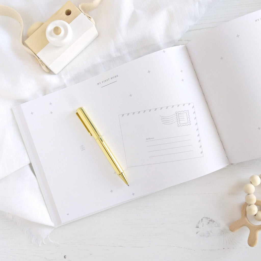 White notebook with a gold pen on a light wooden surface