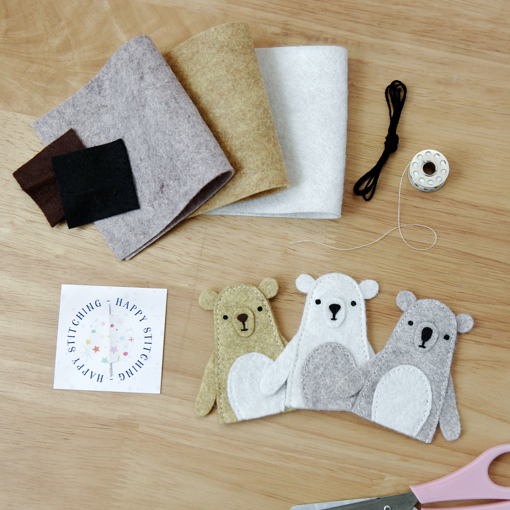 Felt fabric, thread, scissors, and felt animal toys on a wooden surface.