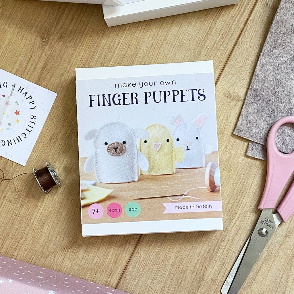 Kit for making finger puppets on a wooden surface with scissors and other materials.