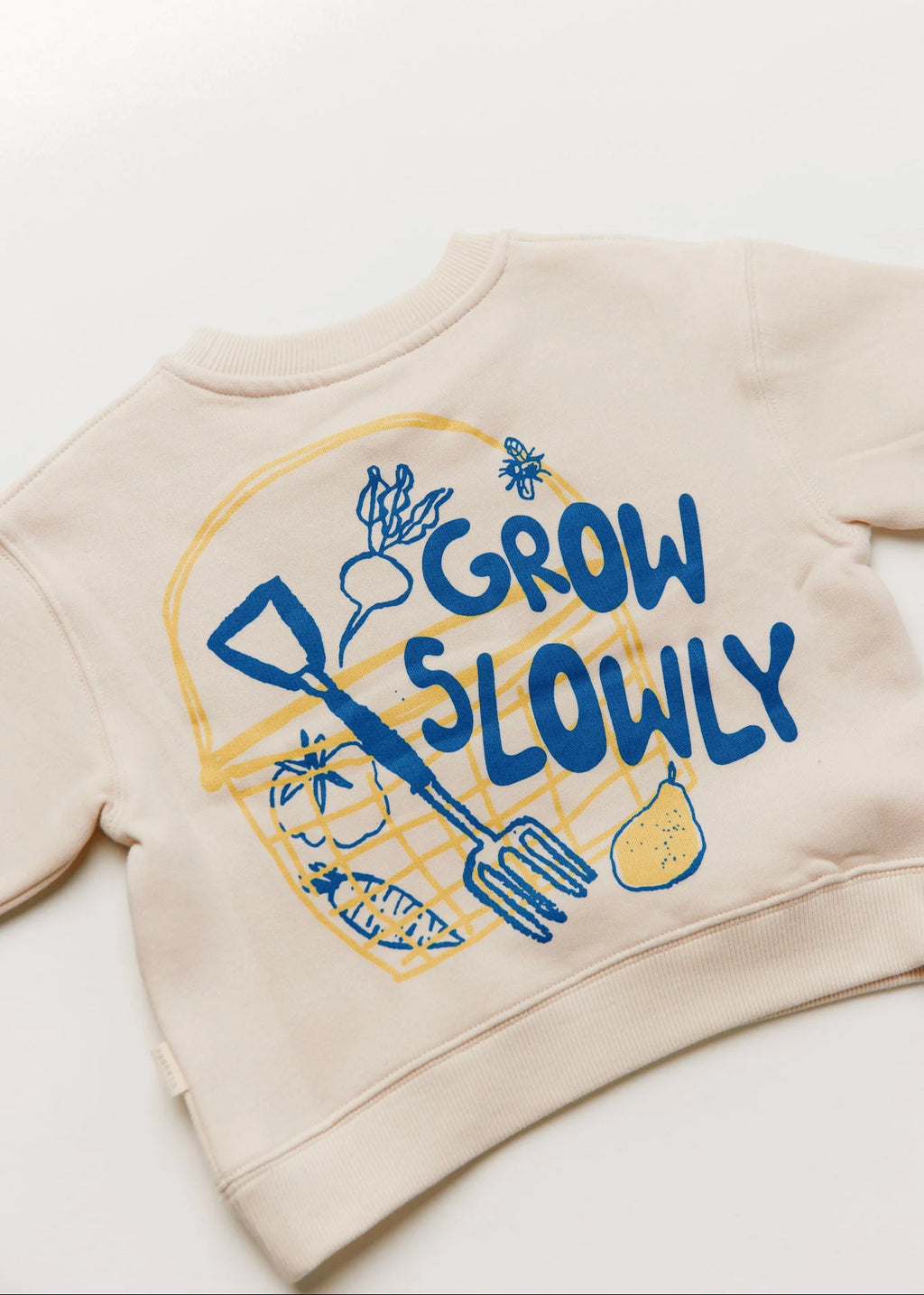 Beige sweatshirt with 'Grow Slowly' text and gardening graphics on a white background