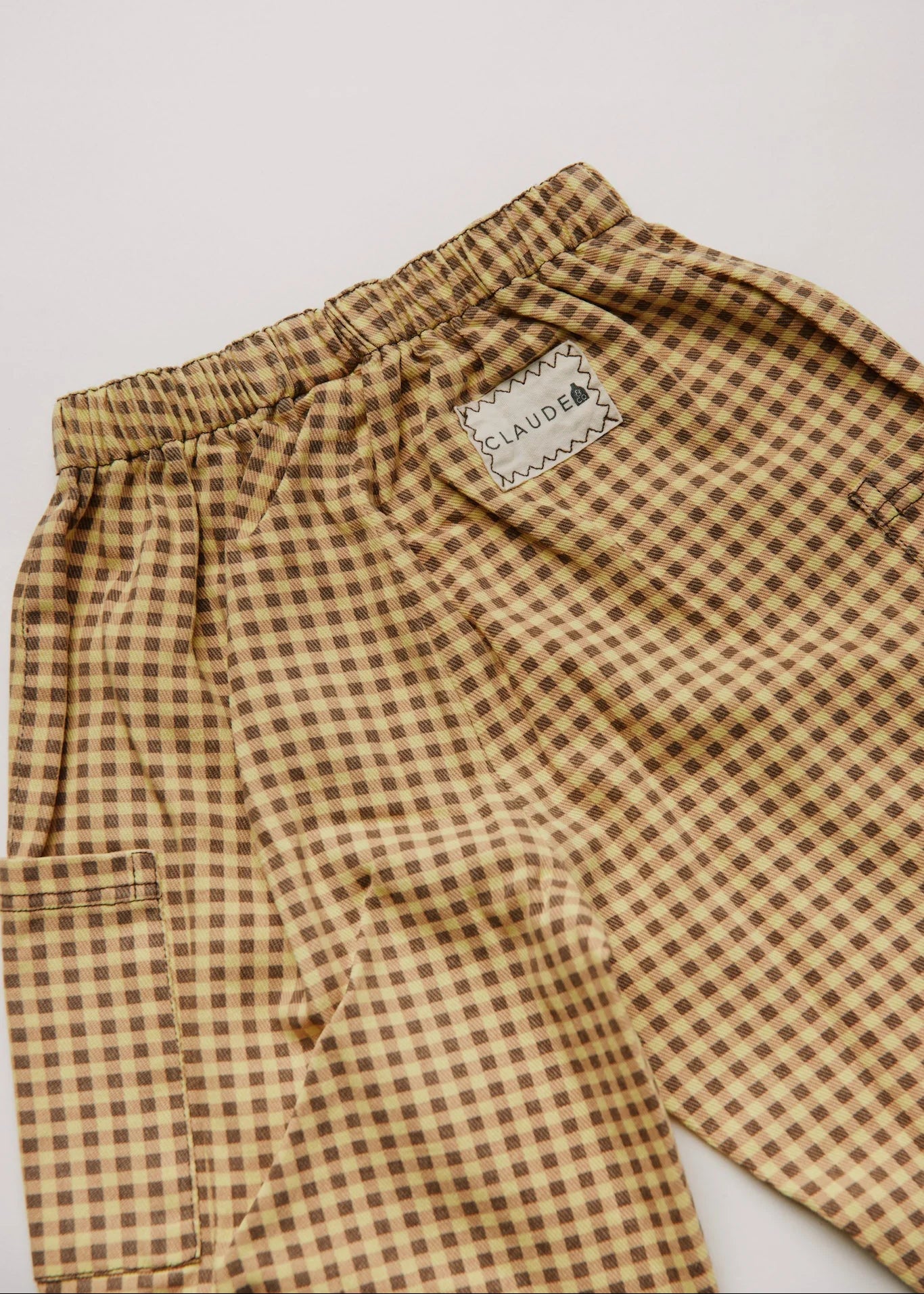 Ochre checkered pants with a brand label on a white background