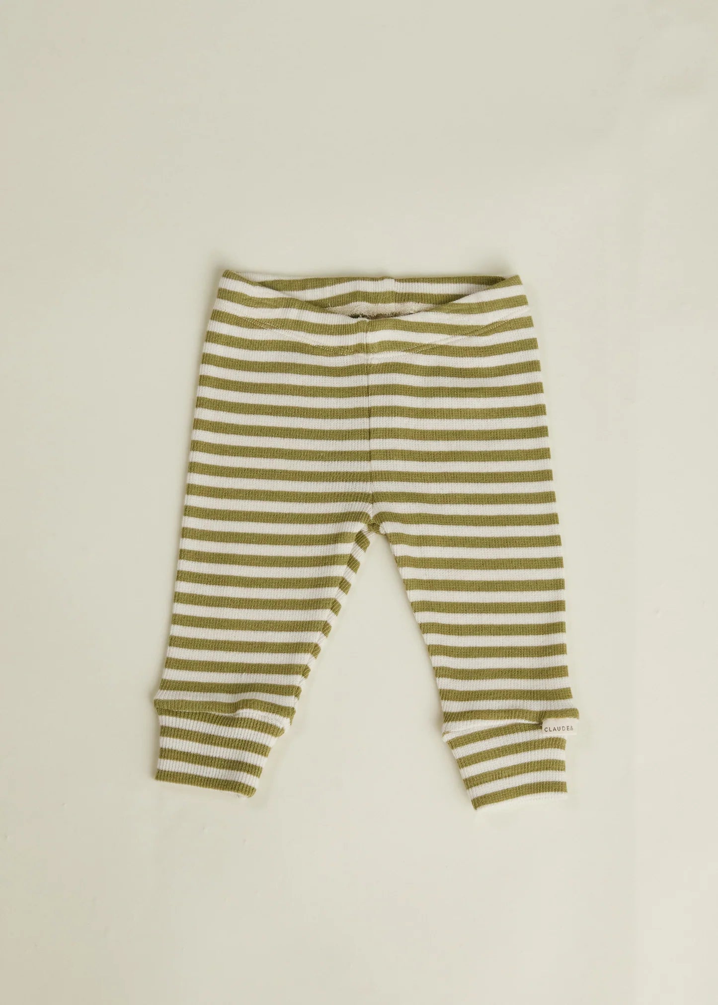 Green and white striped baby leggings on a beige background