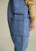 Blue denim apron with 'claude and co' embroidery on a neutral background