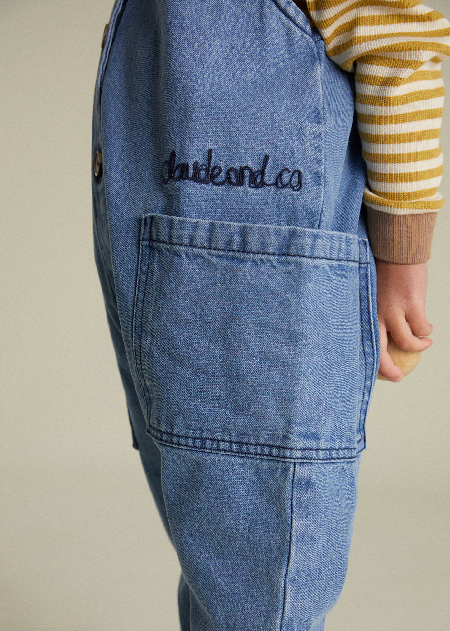 Blue denim apron with 'claude and co' embroidery on a neutral background