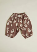 Brown children's pants with white strawberry pattern on a beige background