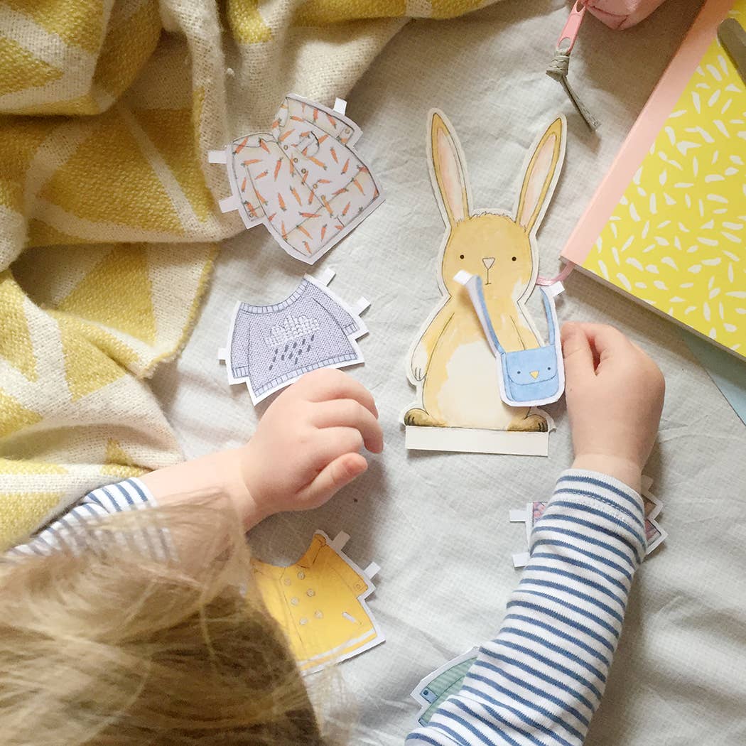 Children playing with paper cutouts of a rabbit and house on a blanket