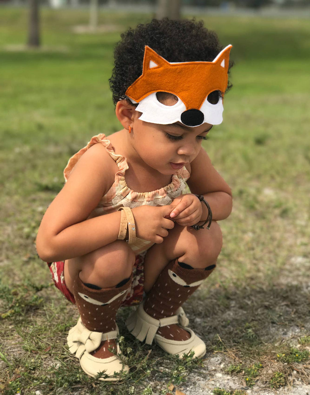 Child wearing a fox mask outdoors on grass