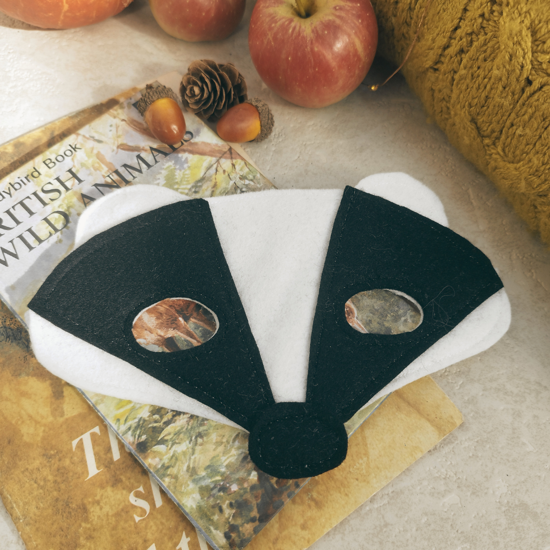 Badger mask on a surface with apples and a book in the background