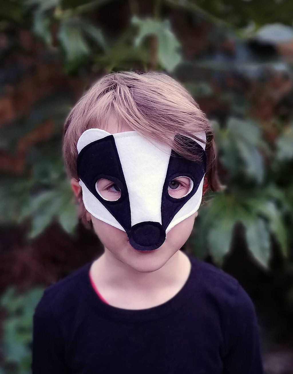 Child wearing a badger mask with a natural outdoor background