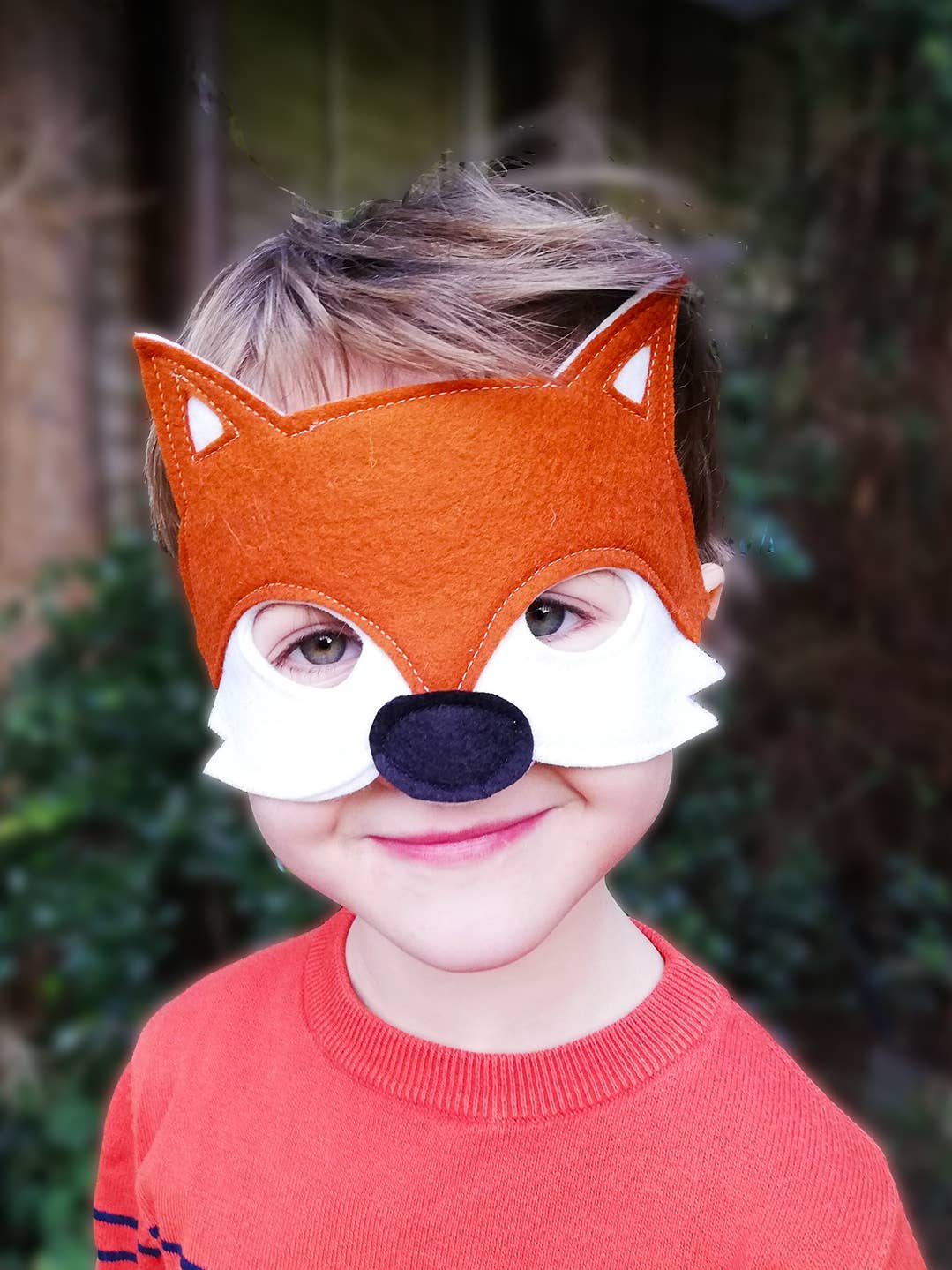 Child wearing an orange fox mask with a blurred background