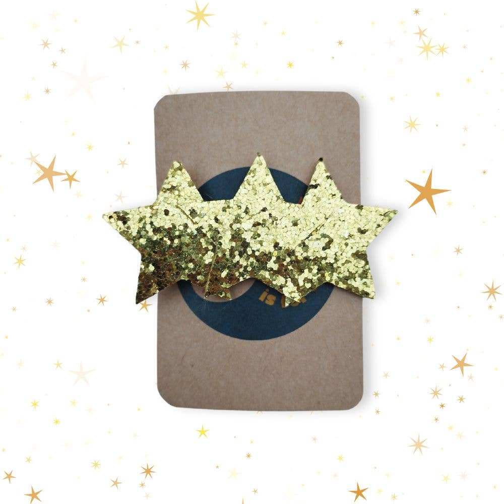 Gold glittery star-shaped hair clip on a brown card with gold stars in the background