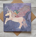 Card with a unicorn and fairy design on a textured surface