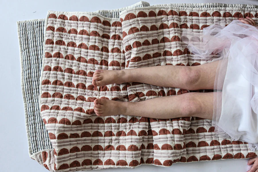 Person lying on a scallop patterned quilt
