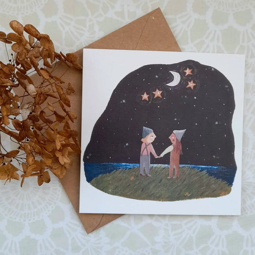 Greeting card with illustration of two people under a starry sky, next to a brown envelope and dried leaves.