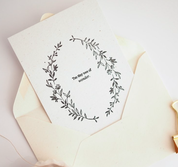 Greeting card with floral wreath design and text on a matching envelope.
