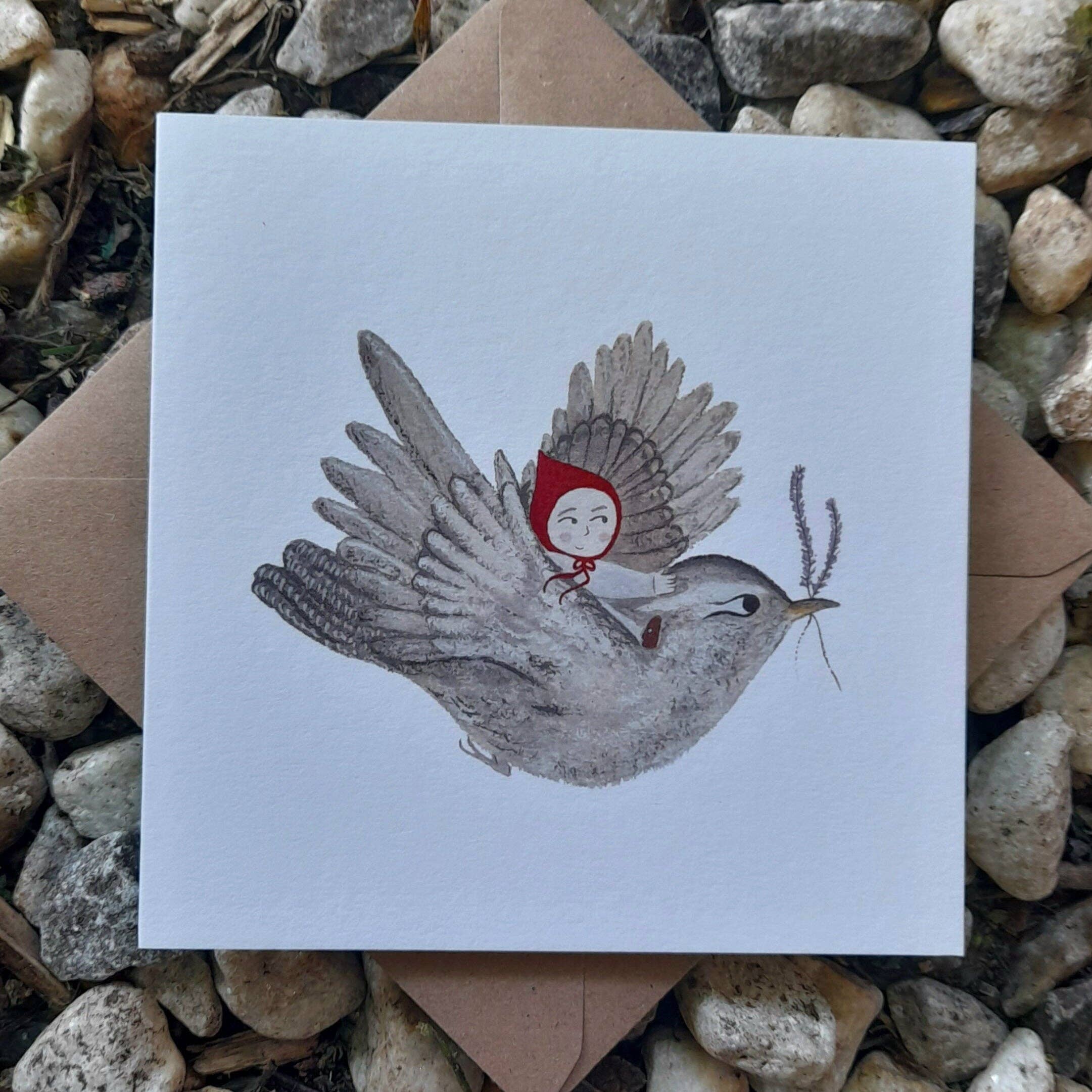 Illustration of a bird carrying a girl with a red hood on a white card, surrounded by stones.