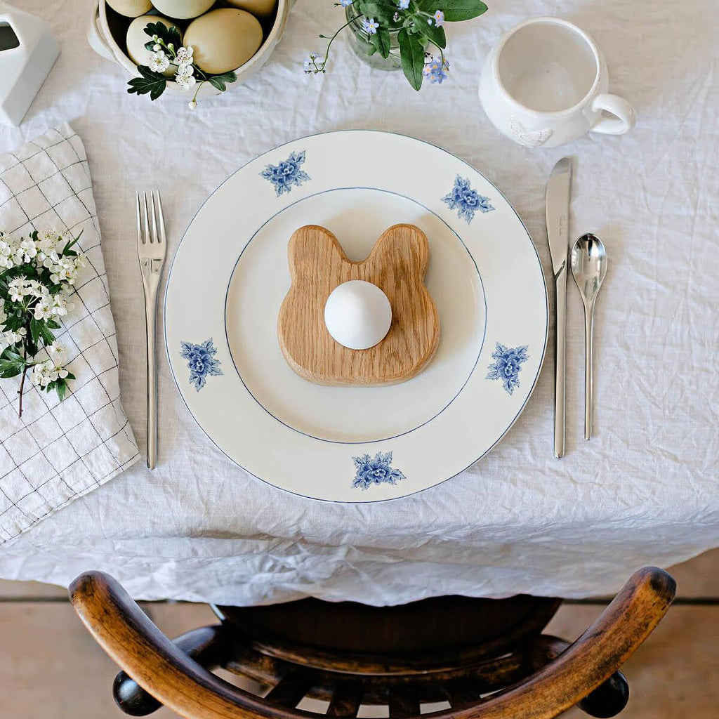 Easter table setting with bunny-shaped toast and decorative eggs on a white tablecloth.