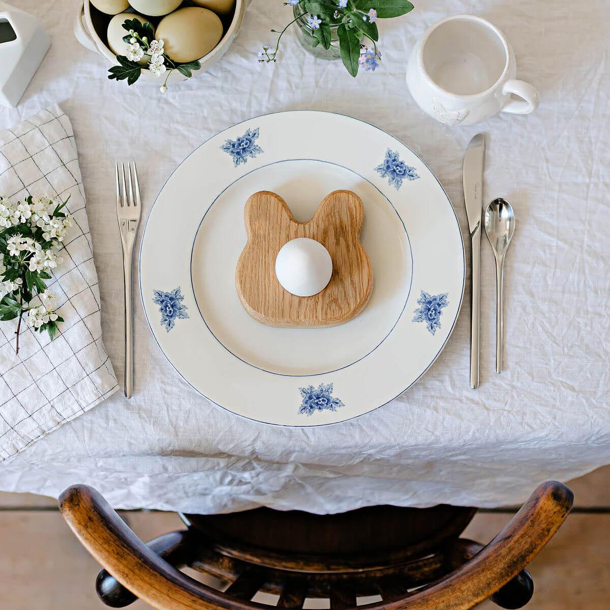 Easter table setting with bunny-shaped toast and decorative eggs on a white tablecloth.